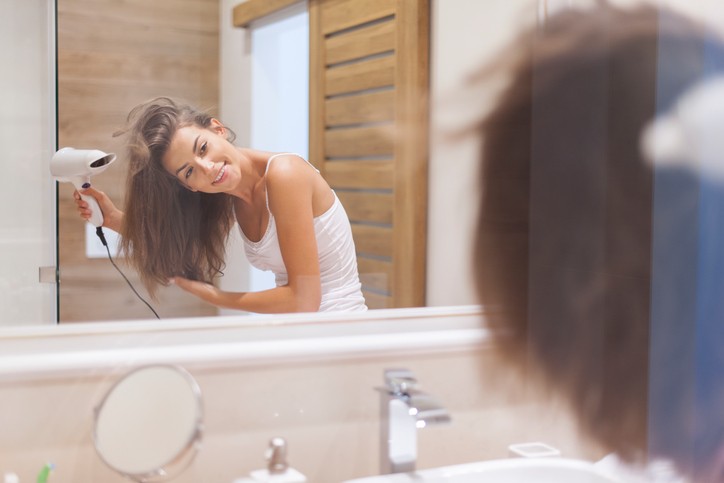 vrouw met spiegel en föhn voor de beste gelaagde kapsel voor dun haar